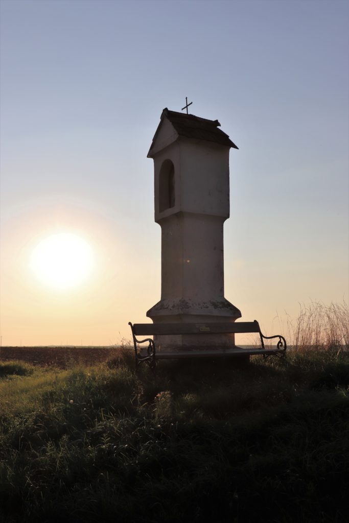 Bank vor einem Marterl und Landschaft mit Sonne